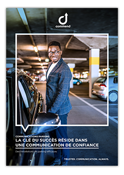 Trusted Parking Communication Systems Smiling man in suit stands by a car in a modern underground parking facility, advertising a communication system.