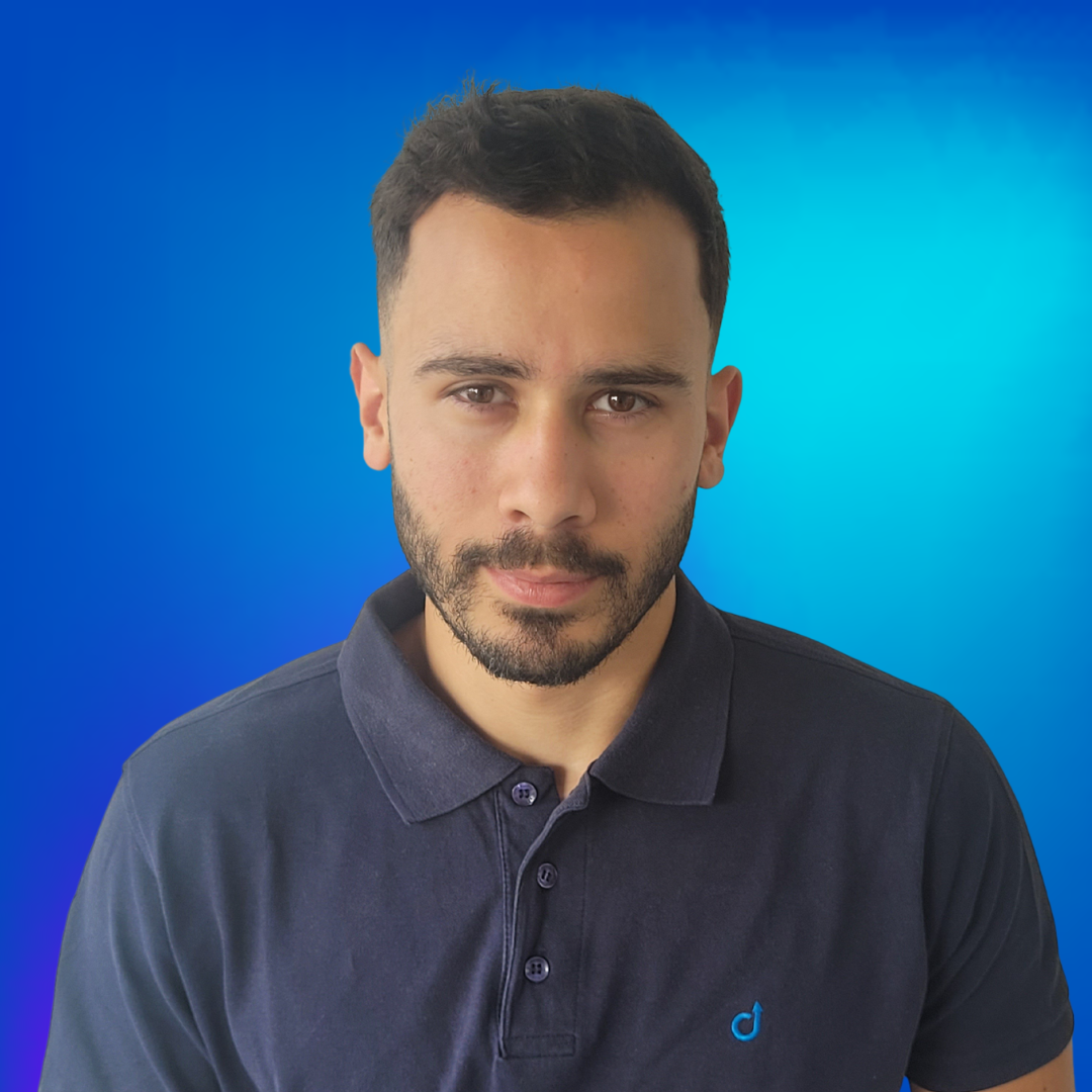 Jeune homme barbu en polo bleu marine sur fond bleu.