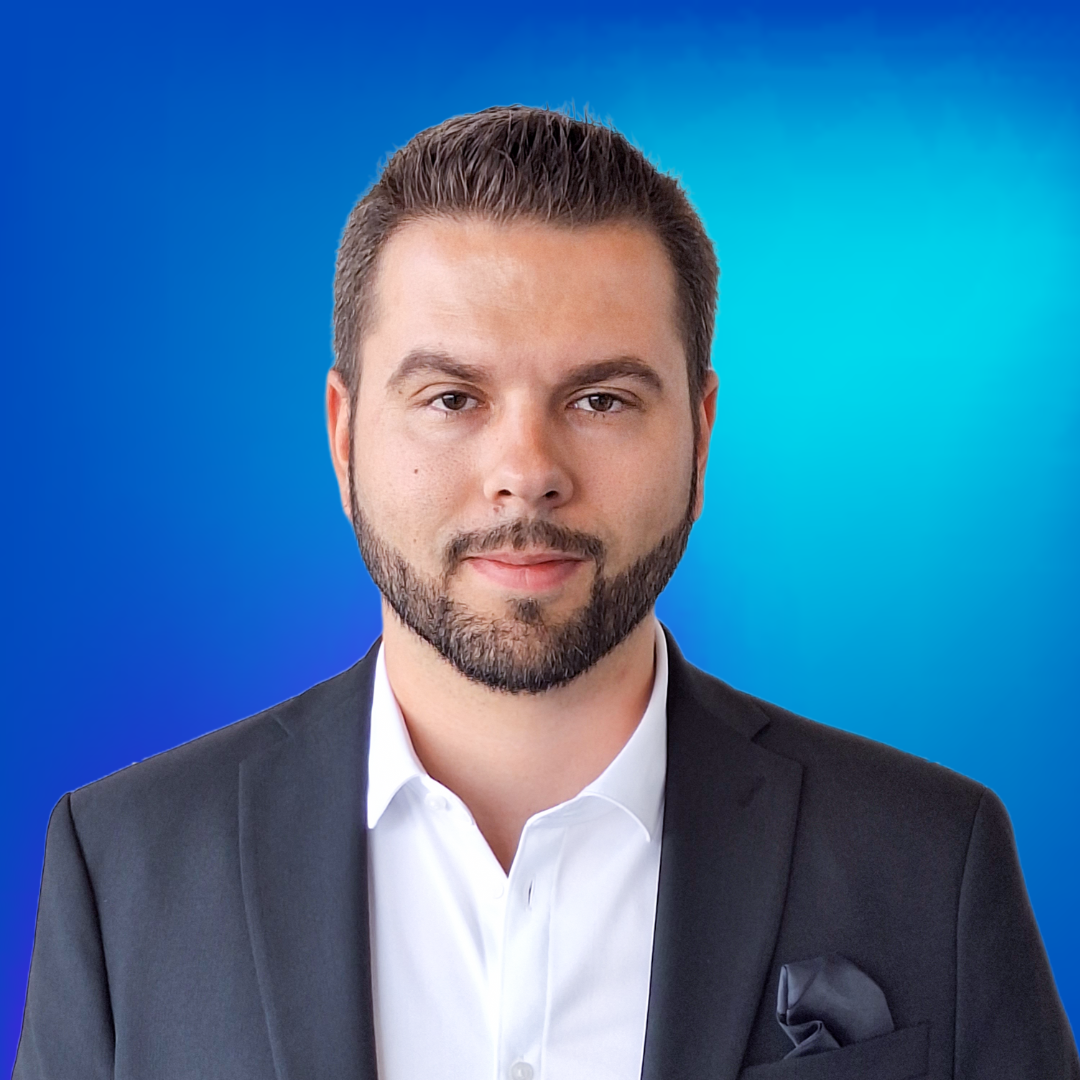 Portrait d'un homme professionnel souriant en costume, fond bleu, représente des solutions d'interphonie.