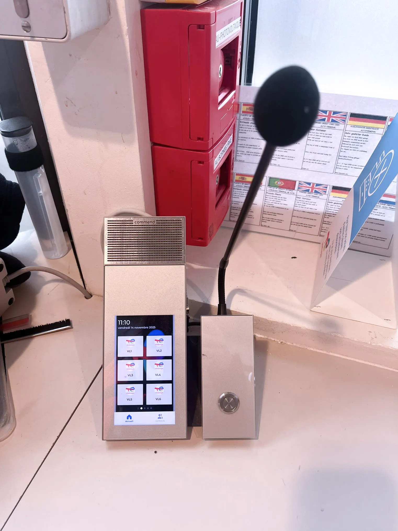 A sleek Commend intercom unit with a touchscreen and microphone, situated next to various service information.