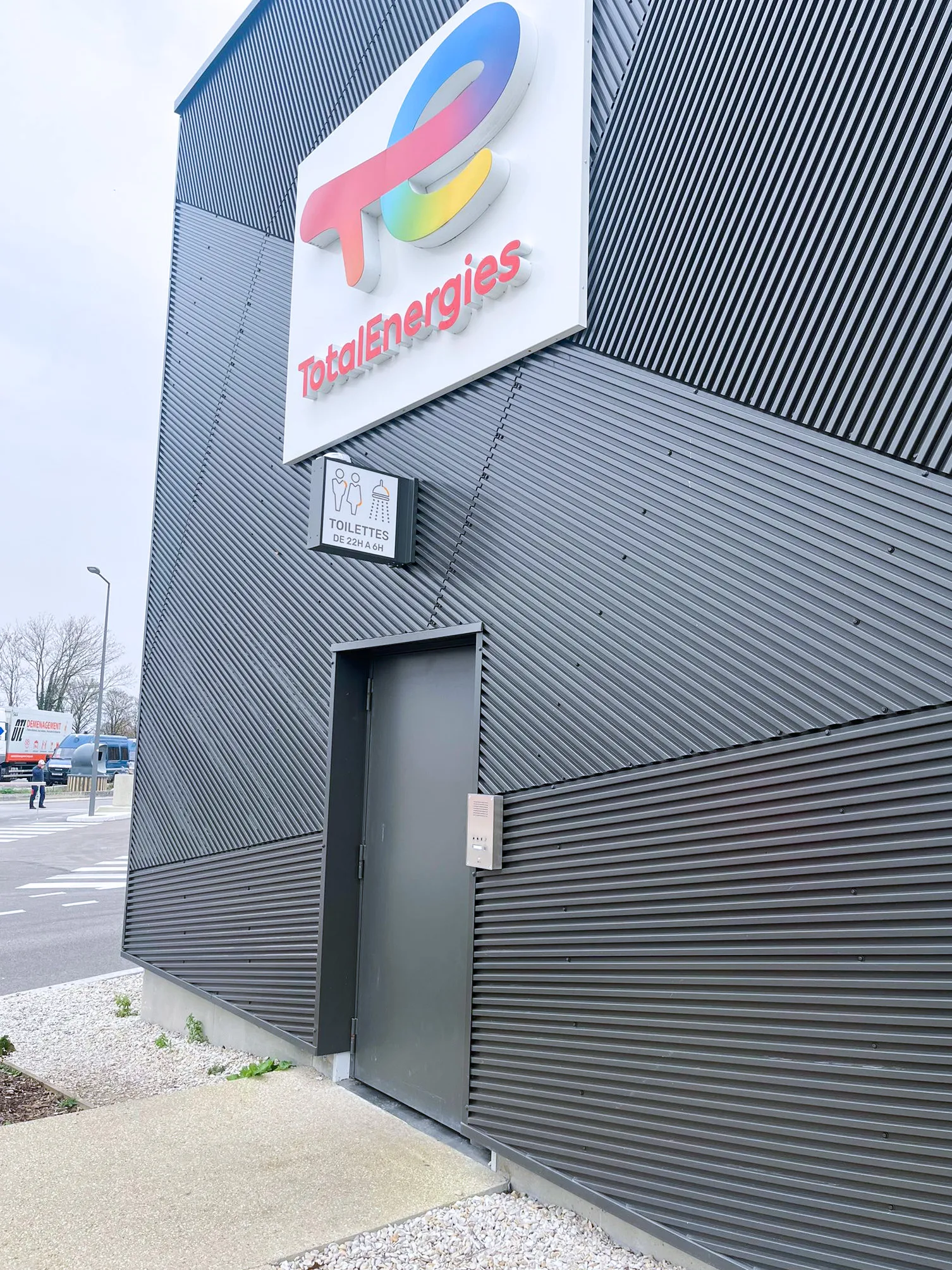 Modern TotalEnergies building with a communication system next to the door for toilets and showers.