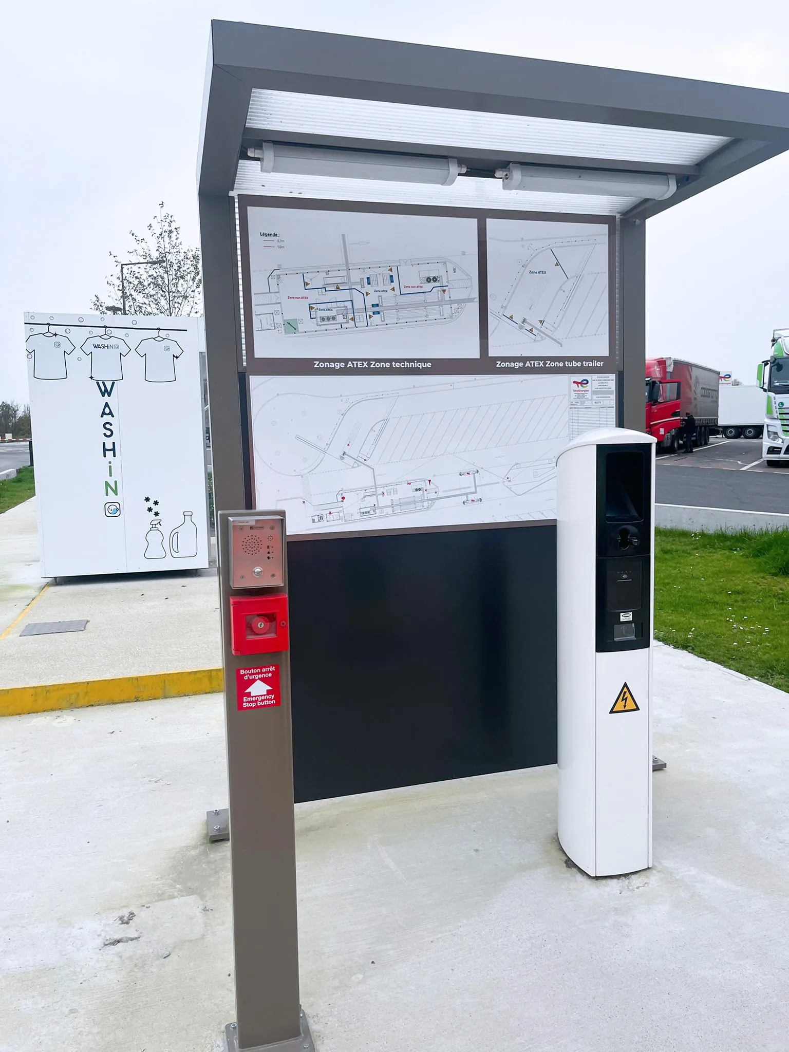 A communication system with an intercom and emergency stop button, alongside an info board showing ATEX zone diagrams at a service area.