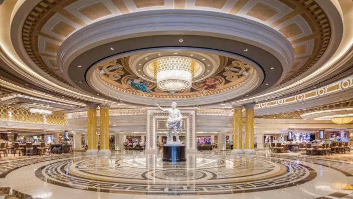 Grand Lobby with Roman Statue & Chandelier Opulent lobby with a classical white statue, marble floor, domed ceiling, and large chandelier.