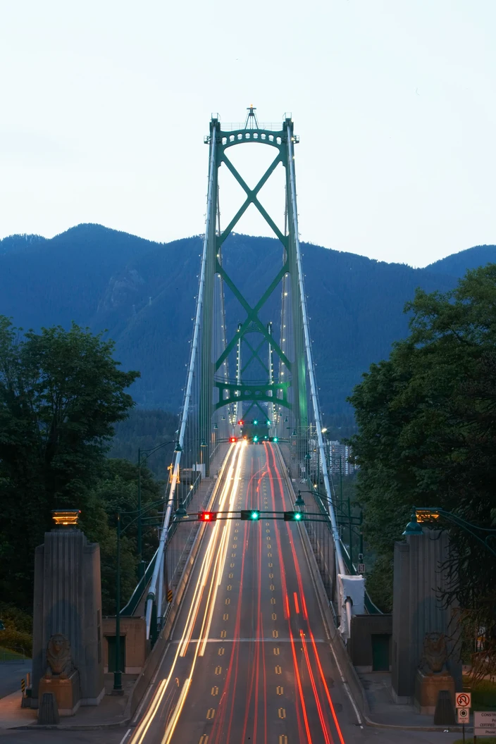 Lions Gate Brücke bei Dämmerung Lions Gate Brücke bei Dämmerung mit Lichtspuren von Autos und Bergen.