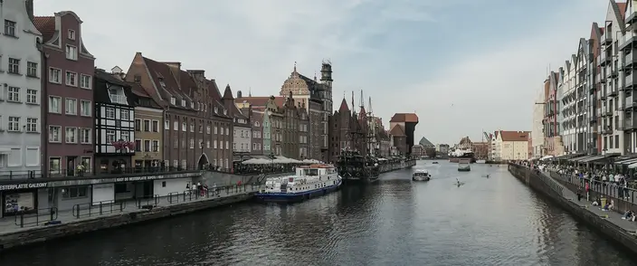 Gdansk Waterfront Charm Historic waterfront in Gdansk, Poland, with colourful buildings, river, boats, and people.