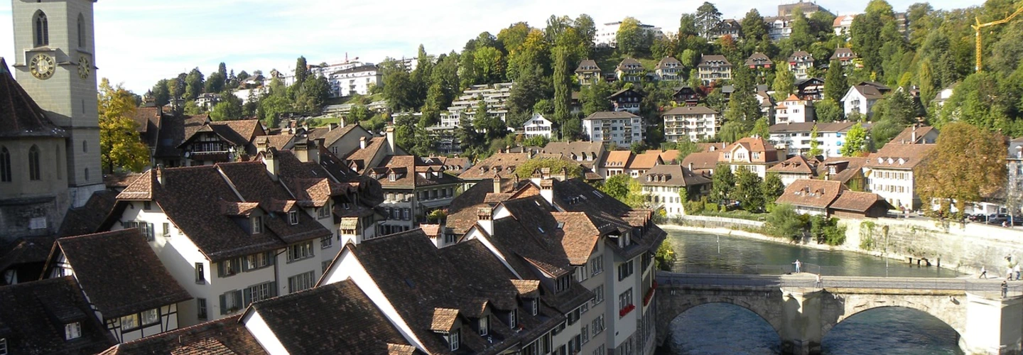 Bern Old Town, Aare River, Switzerland Panoramic view of Bern Old Town, Switzerland, with river, arched bridge, church, and houses on hills.