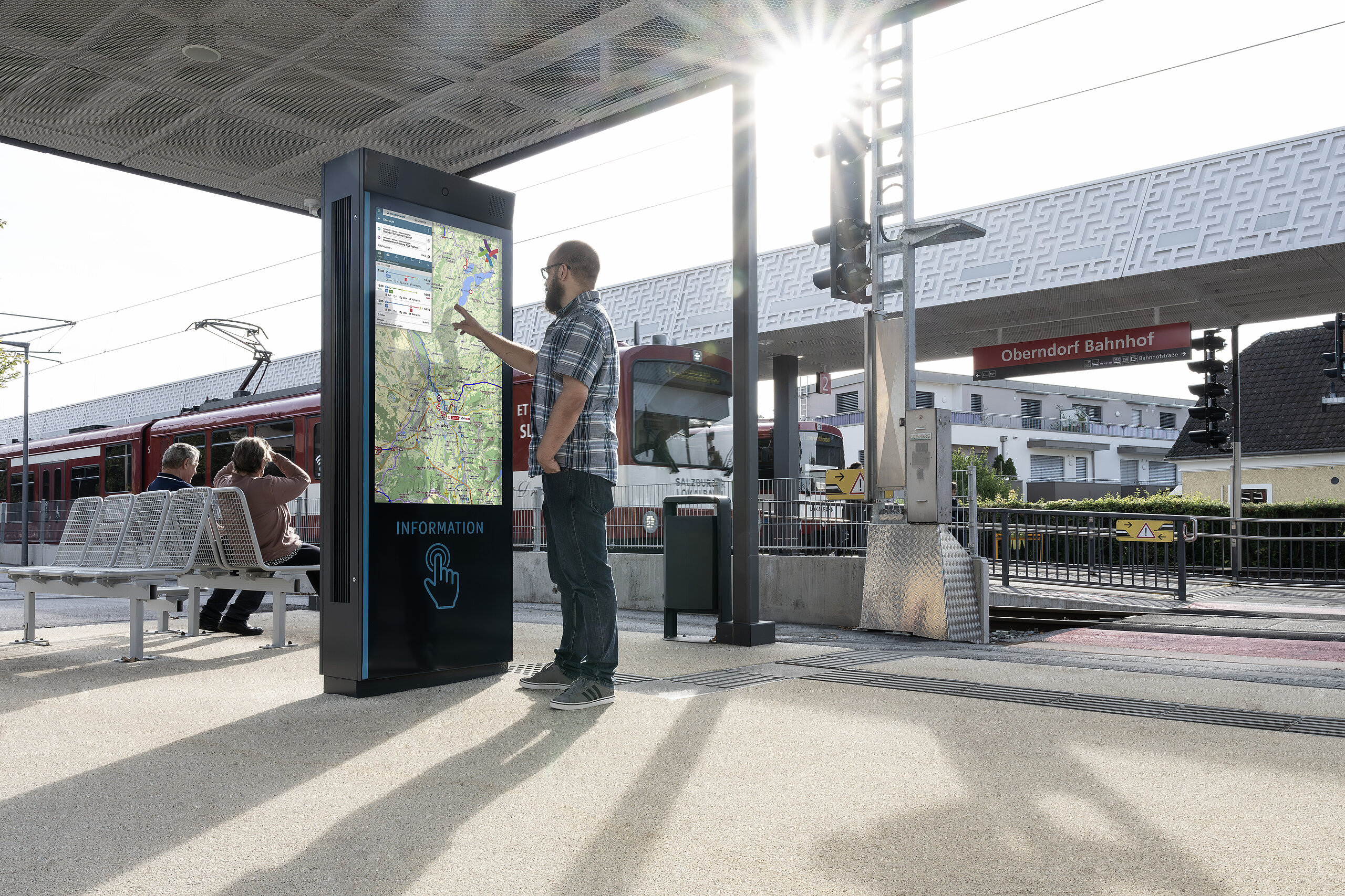 Uomo che tocca schermo informativo con mappa alla stazione Oberndorf.