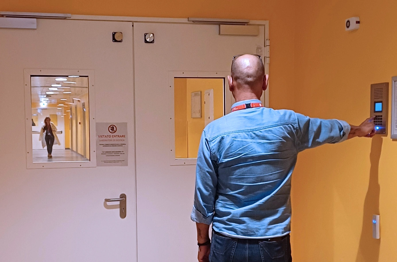 Hospital visitor uses wall intercom to request entry through secure ward doors with communication system