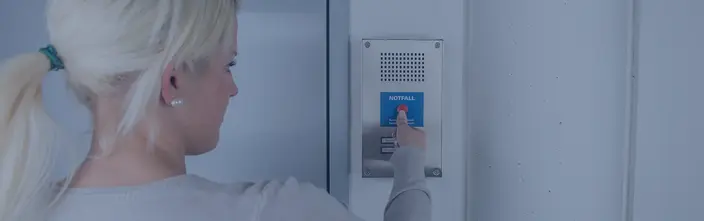 Emergency Intercom Call Woman pressing a red emergency button on a metallic intercom.