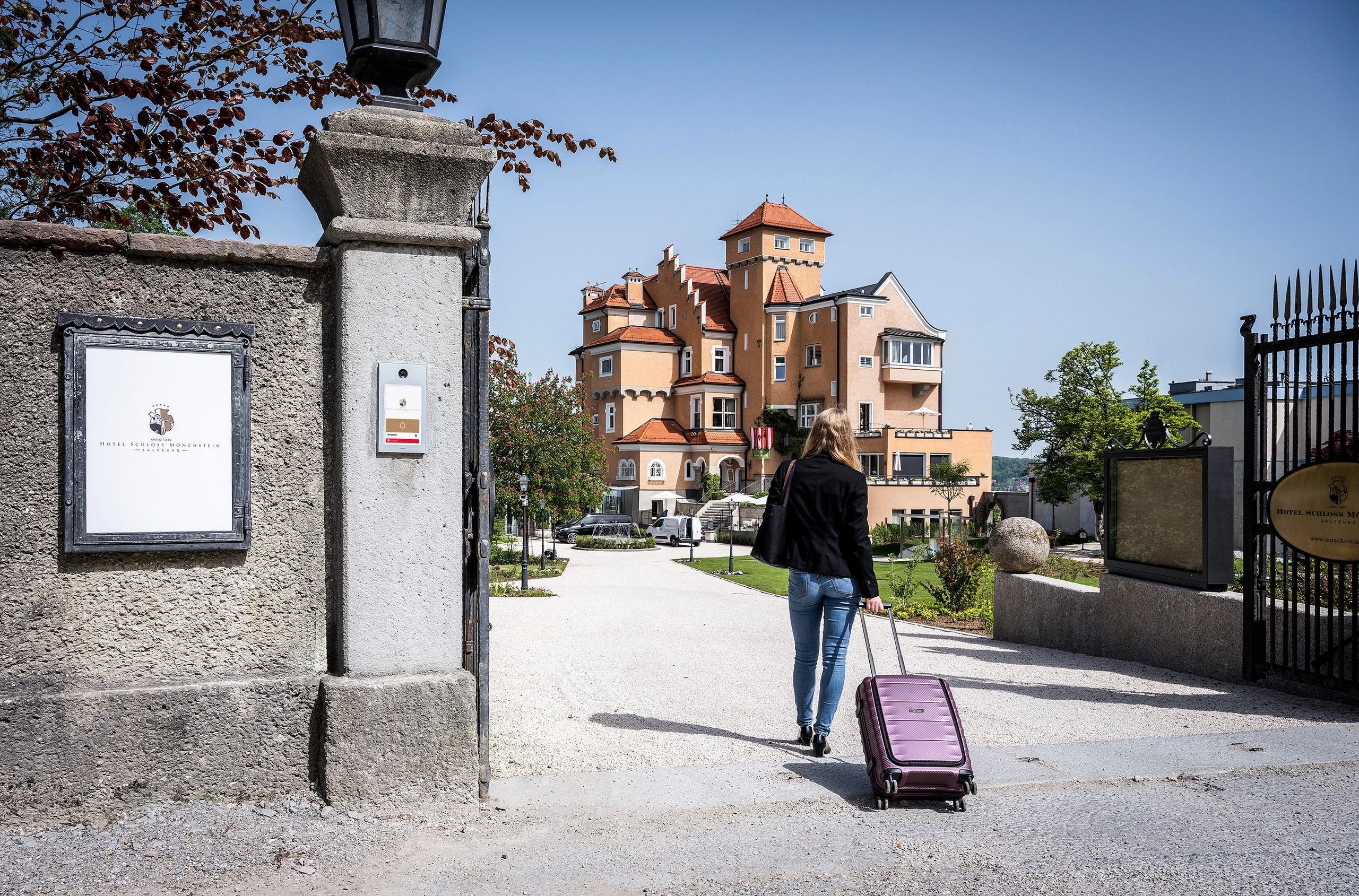 Guest enters hotel through gate with modern touchscreen intercom for visitor access