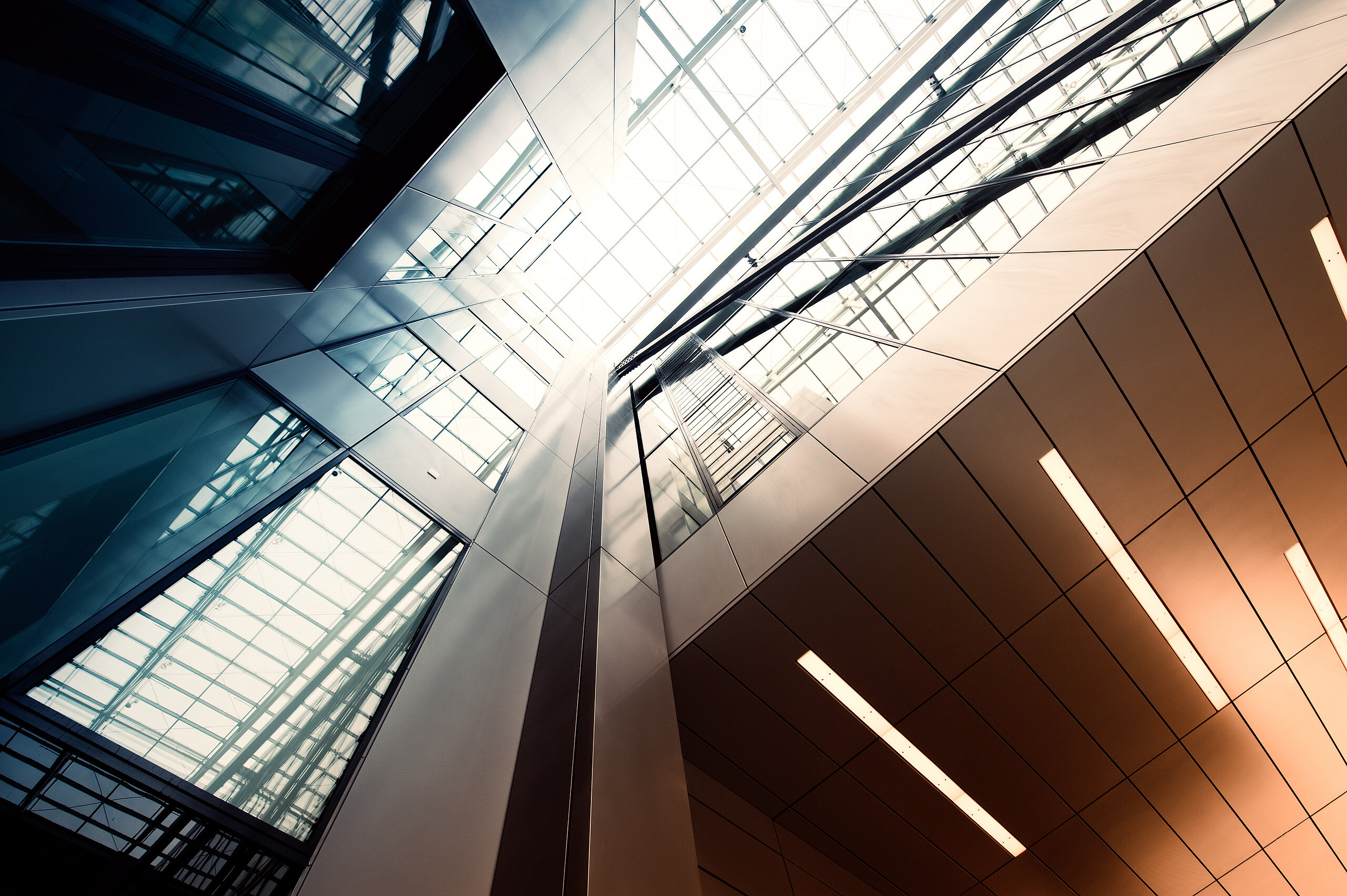 Architettura moderna, interni luce Interno di edificio moderno con soffitto in vetro, travi metalliche e illuminazione lineare calda.