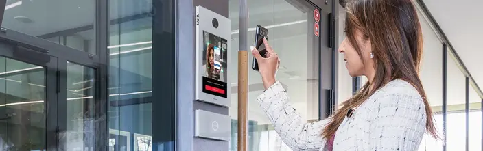 Mobile Access for Secure Entry Woman scanning QR code on phone at sleek intercom for building access.