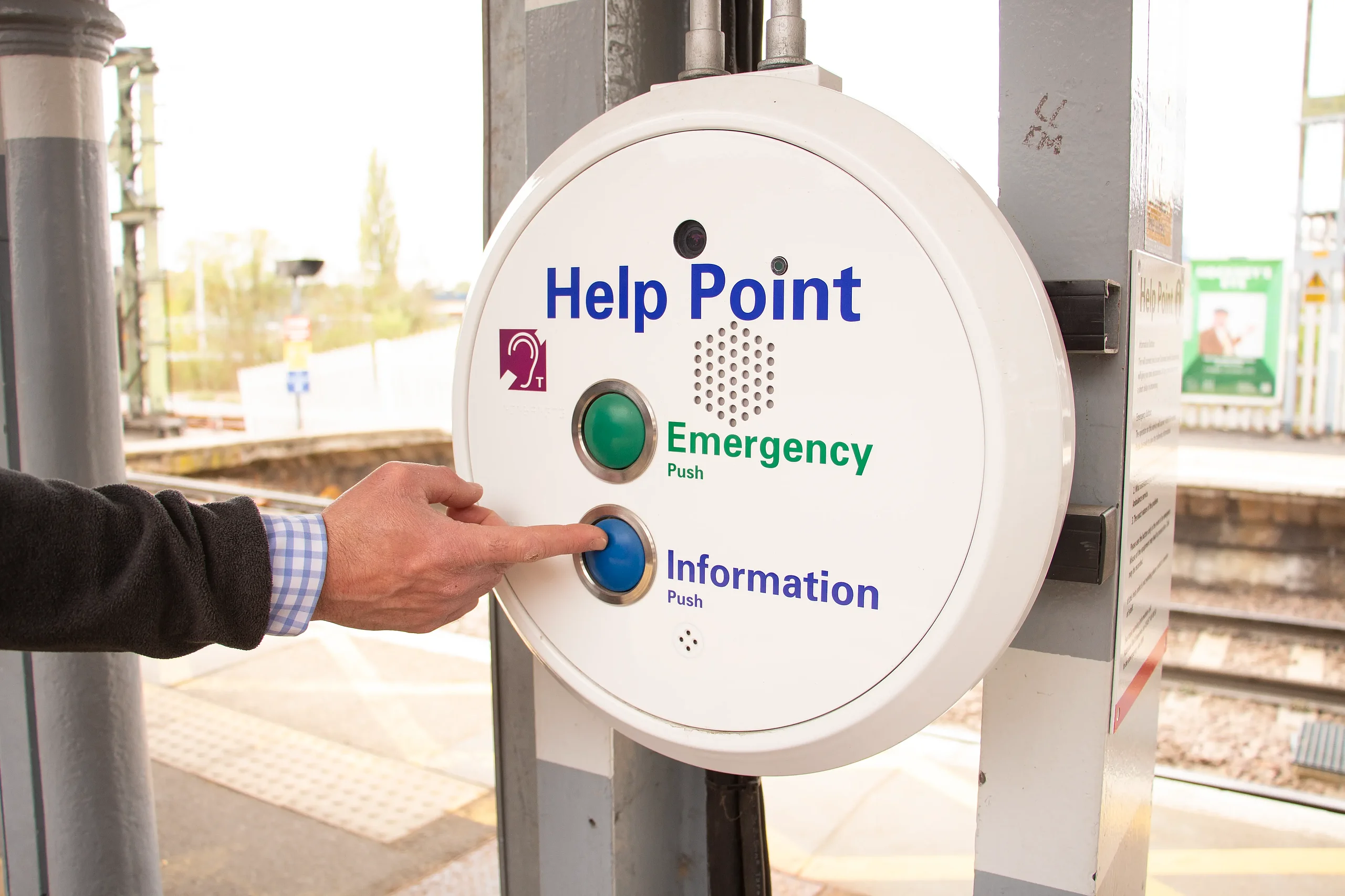 Passenger using railway help point intercom for information at station