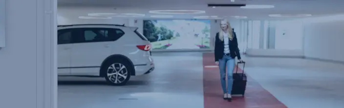 Parcheggio moderno, partenza sicura Donna con bagaglio lascia un parcheggio moderno con un SUV bianco.