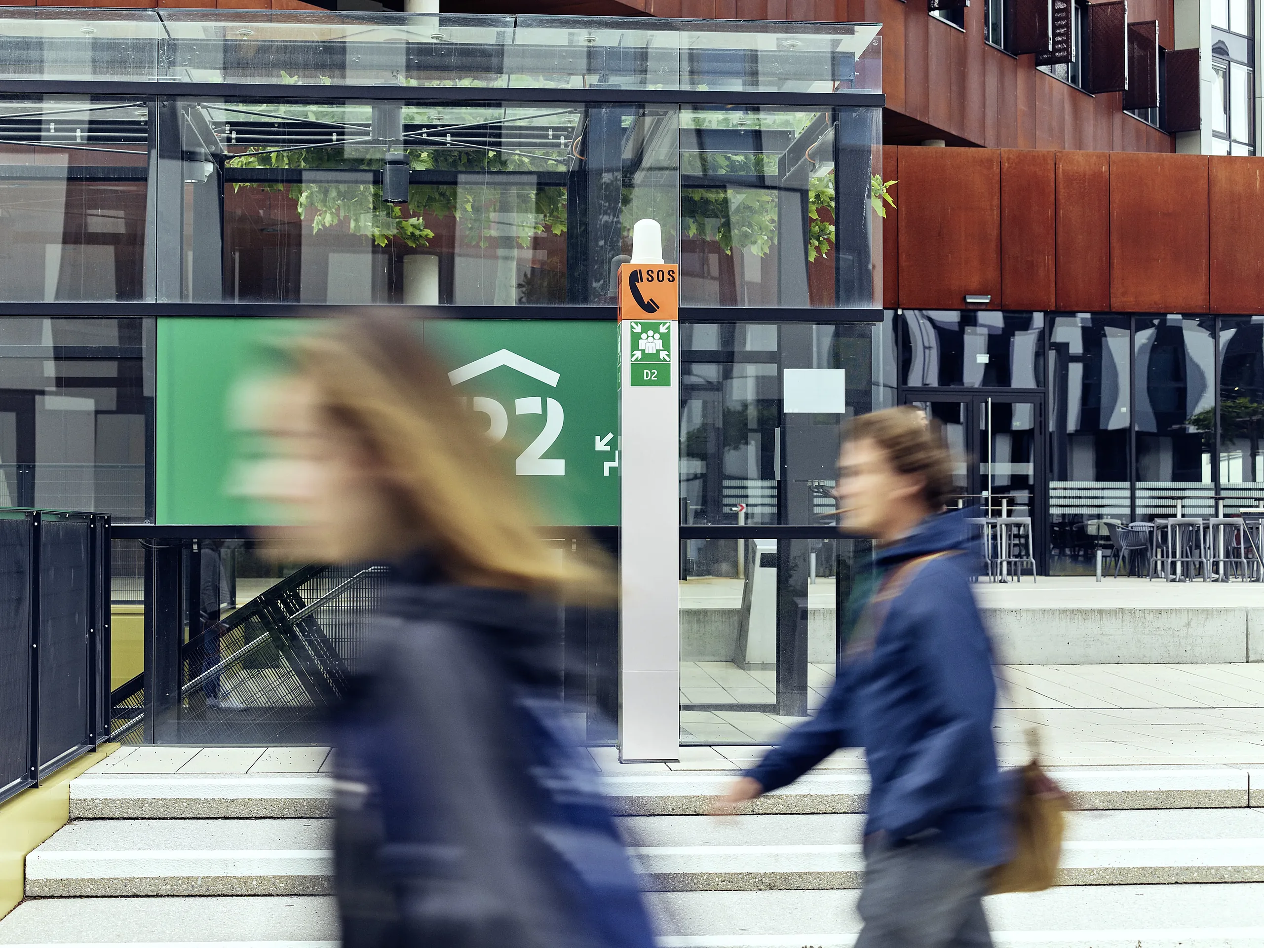 Emergency Intercom station near modern building with people walking by