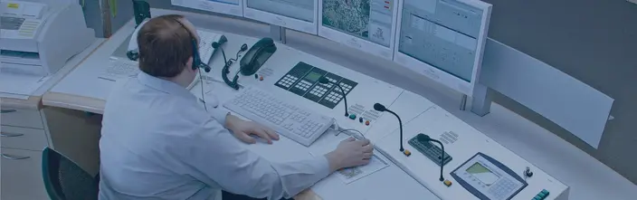 Control Room Operator at Console Operator using a communication system at a multi-screen control desk.