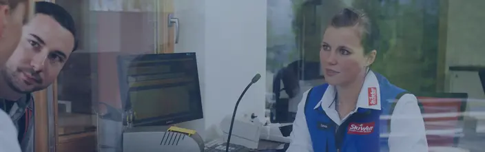 Hombre hablando con empleada de 'SkiWelt' a través de cristal usando un puesto de interfonía.