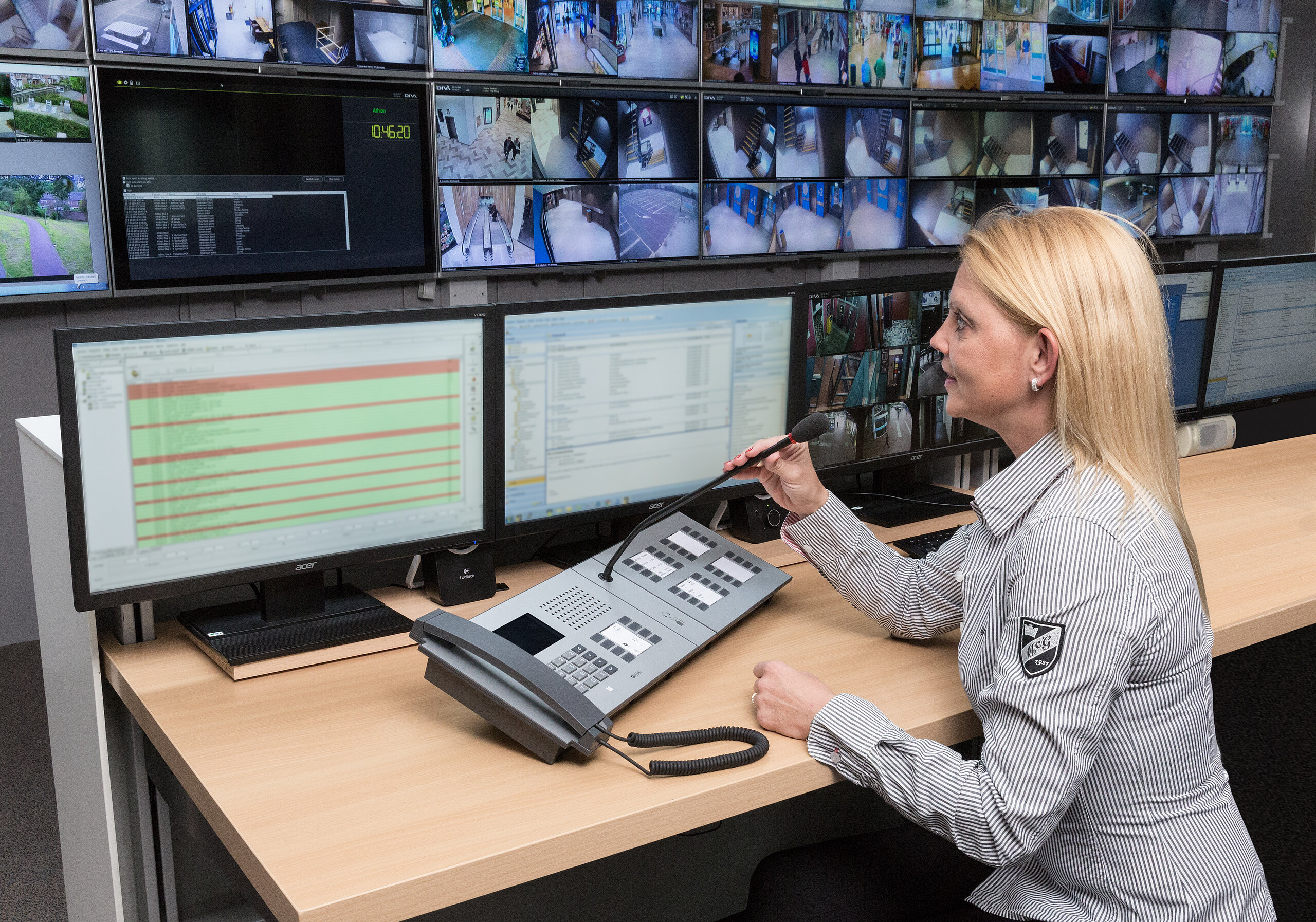 Operatrice che usa un terminale interfonico con microfono a collo d'oca in una sala di controllo sicurezza.